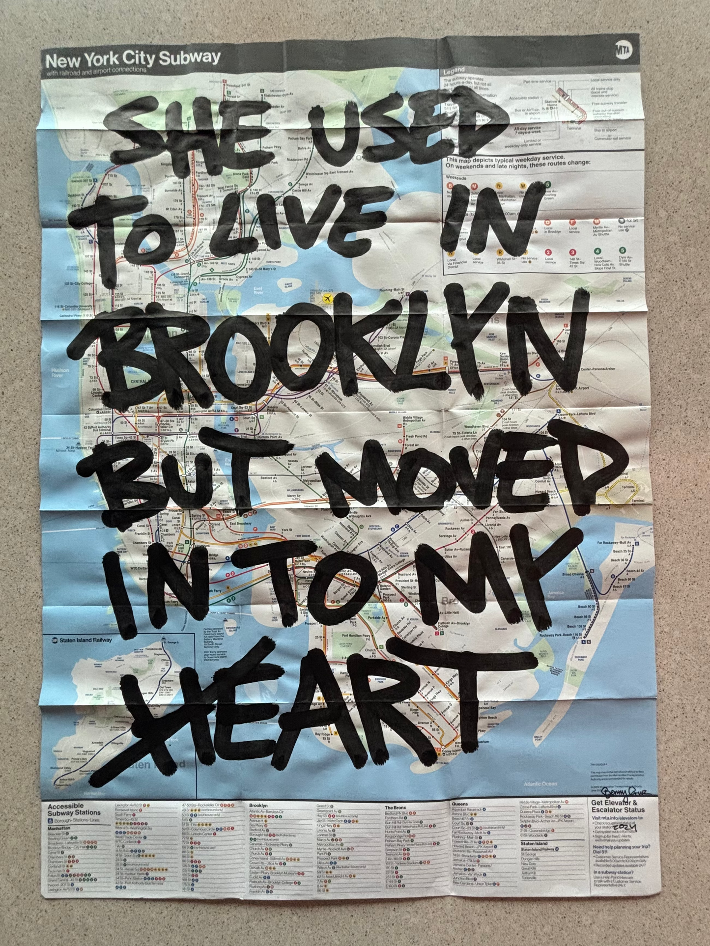 Map of New York City Subway with text 'She used to live in Brooklyn but moved in to my heart' on a wall.
