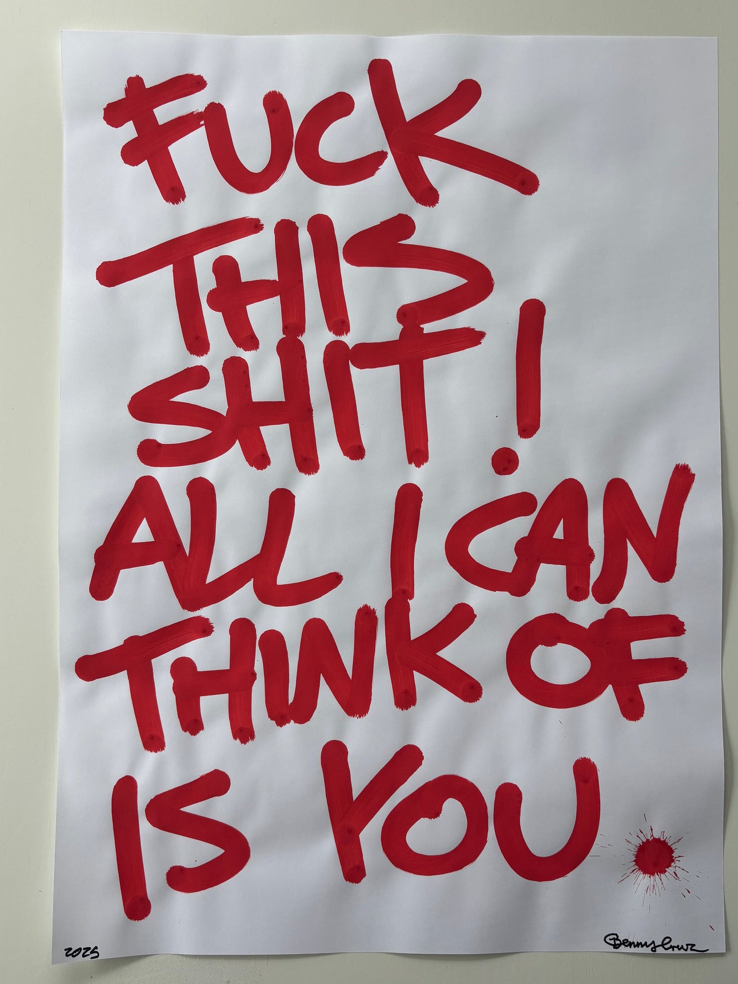 A white poster print featuring bold red handwritten-style text that reads, 'FUCK THIS SHIT! ALL I CAN THINK OF IS YOU,' with a small red splatter detail near the lower right. The poster is photographed against a light gray background.