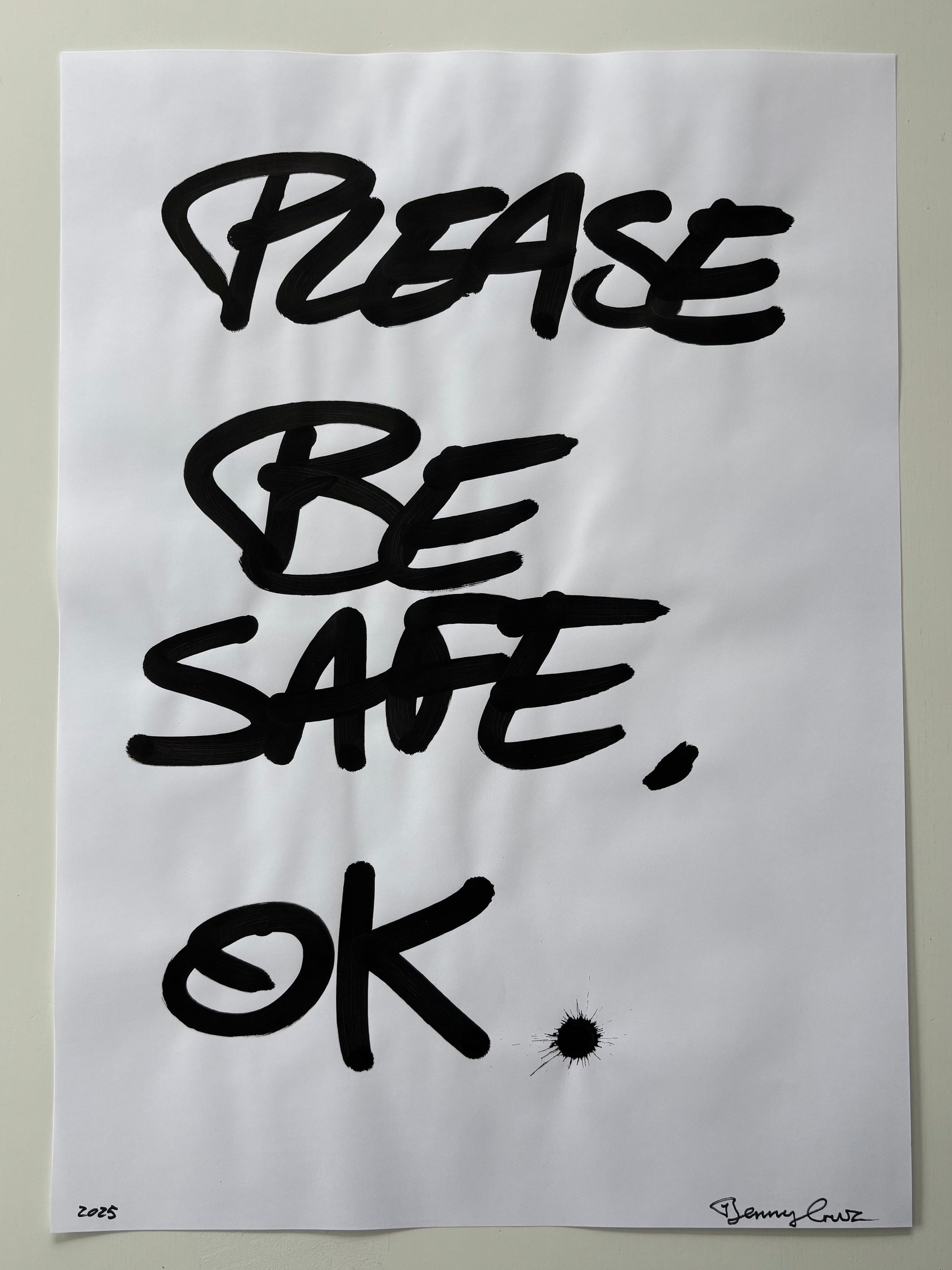 A white art print featuring the hand-lettered text 'PLEASE BE SAFE, OK' in bold black ink, displayed against a neutral light gray background.
