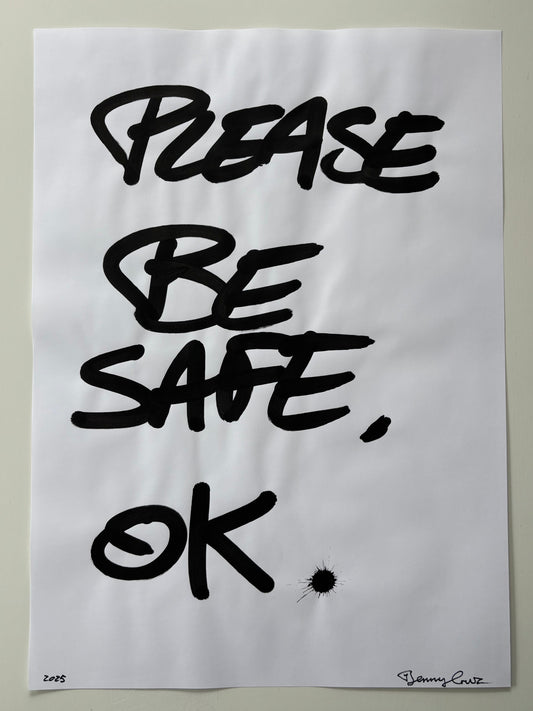 A white art print featuring the hand-lettered text 'PLEASE BE SAFE, OK' in bold black ink, displayed against a neutral light gray background.