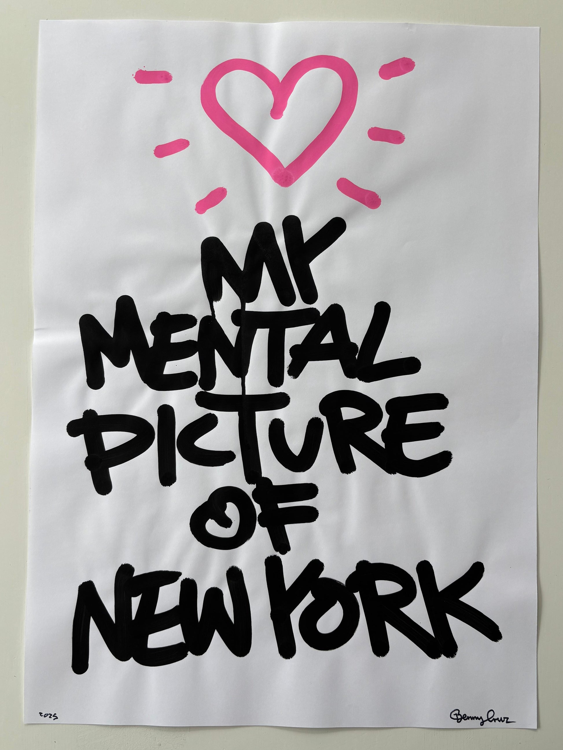 A white art print featuring the text 'MY MENTAL PICTURE OF NEW YORK' in black hand-lettered font, with a pink heart and radiating lines at the top, displayed against a light beige wall.